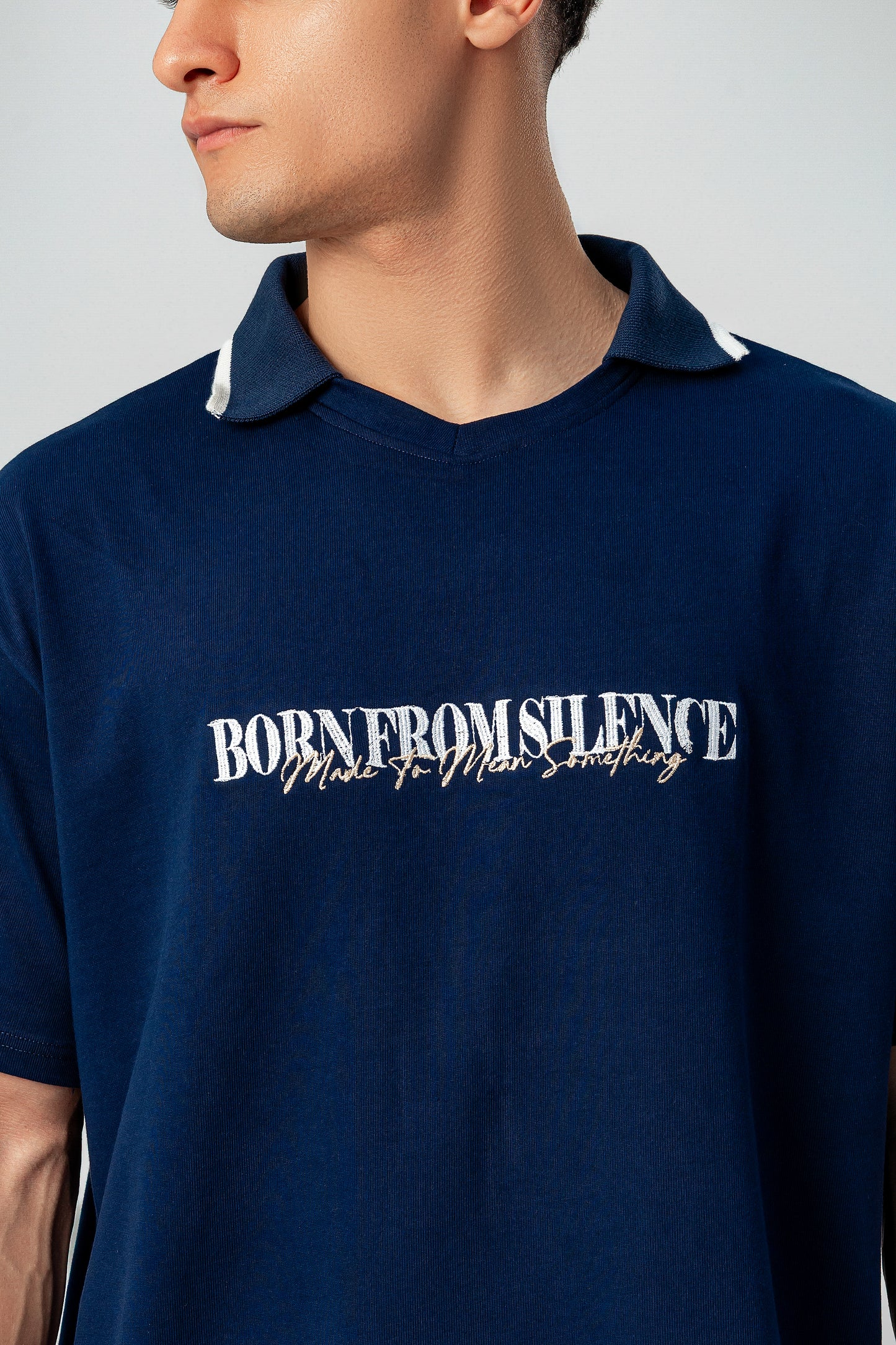 Close-up of LUNEX navy polo collar and "Born from silence" print