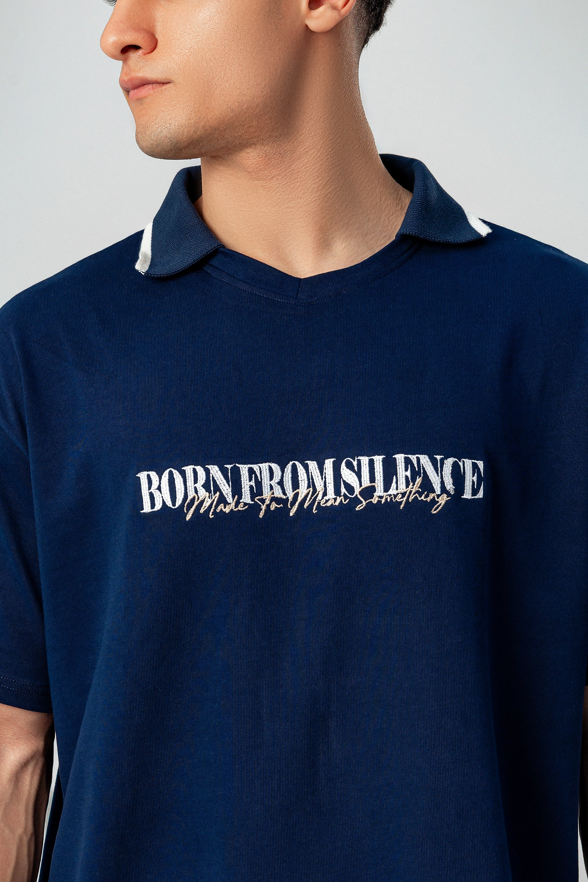 Close-up of LUNEX navy polo collar and "Born from silence" print